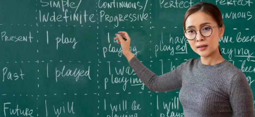 Woman teacher in front of black board.